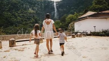 镜头跟随幸福的年轻母亲和两个孩子走向惊人的丛林瀑布景观在斯里兰卡慢动作。