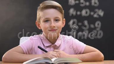 在数学课上，男孩坐在课桌上，看着摄像机，看着教育