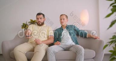 两名在电视上观看足球比赛的白种人的特写照片，他们因坐在沙发上而沮丧