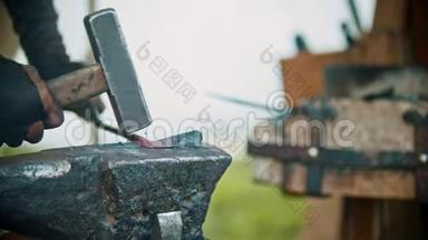 铁匠在他的车间里加工一个铁的细节-用锤子敲打金属片，弯曲它