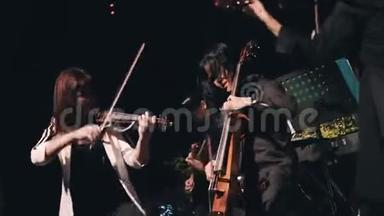 三位小提琴手在舞台上嬉戏打闹. 器乐合奏的出色表现.. 很酷的摇滚乐队。