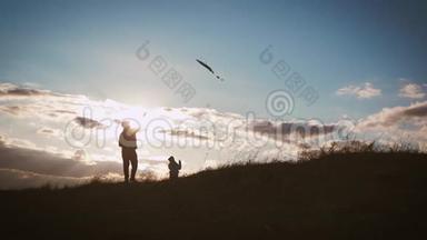 幸福的家庭父亲和孩子女儿在日落时在草地上放风筝。 有趣的家庭时光。 友好家庭的概念