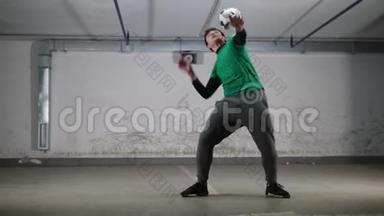 地下停车场。 一个年轻灵巧的足球运动员训练足球技巧。 平衡他身体上的球