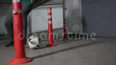 地下停车场。 一个足球运动员训练他的足球技能。 引导球踢过障碍物。 关门