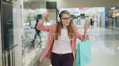 <strong>免费</strong>的年轻女学生正在<strong>购物</strong>中心听音乐，戴着耳机跳舞唱歌，享受着快乐