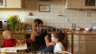 聪明的妈妈，厨房里有两个孩子。 一个女人喂两个孩子。 母亲节