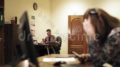 办公桌前的年轻女商人和<strong>后面</strong>的同事都在敲办公室的电话