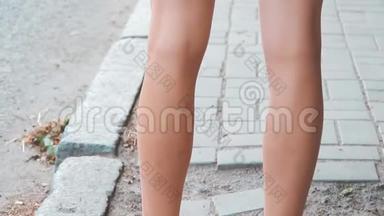 穿夏季拖鞋的女腿.. 一个年轻女孩腿上的橡胶凉鞋。 一个女人站在路边，走过去。