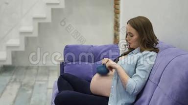 孕妇在家坐在扶手椅上<strong>给宝宝</strong>玩可爱的小袜子，`建议这样可以帮助<strong>宝宝</strong>