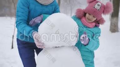 妈妈和她的小女儿在冬天玩得很开心，在街上<strong>堆雪人</strong>。