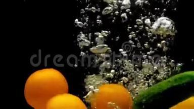 Tomatos和黄瓜在黑色背景的透明水中掉落