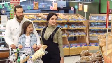 幸福的家庭和小女孩从食品店的货架上挑选面包。
