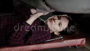 漂亮的女孩，一个<strong>汽车</strong>修理工，躺在车下转动螺母