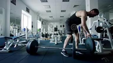 年轻的运动员在健身房锻炼前，要把体<strong>重放</strong>在杠铃酒吧