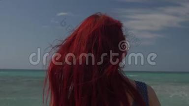 一个红头发的女人在海浪的背景下迎风飞翔的背影