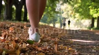人们在秋天公园散步。 脚下落叶.. 优雅的女人穿<strong>白色短裤</strong>。 金秋概念