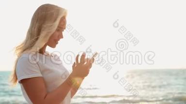 漂亮的少女在海滩上使用智能手机，<strong>背景</strong>是<strong>大海</strong>和地平线