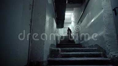 年轻的黑发女人穿着红色<strong>无袖</strong>夹克，在黑暗中走着长长的楼梯。