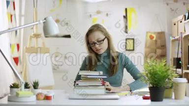 年轻漂亮的女人把书扔出桌子，打开笔记本电脑上网