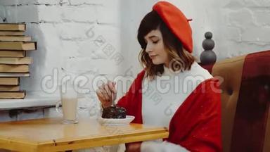 白种人的可爱女孩穿着红色贝雷帽，坐在咖啡馆里，在桌子上<strong>切蛋糕</strong>，这是一种鸡尾酒