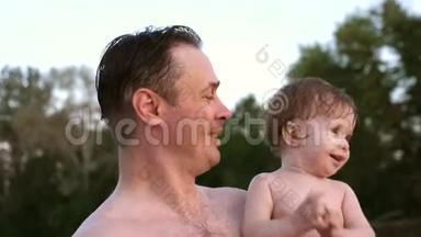 快乐的宝宝在爸爸的手`拍手。 爸爸和开朗的孩子在海滩上放松。 孩子笑着快乐着