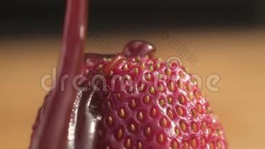 巧克力焦糖糖浆将一股浓稠的水流注入成熟多汁的新鲜红草莓的顶端，上面有大颗种子。 慢慢地往下滴
