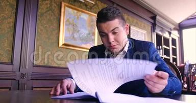 一个年轻的商人坐在别致的办公室里，对一份纸合同感到不满，拒绝签字，生气，不愿签字