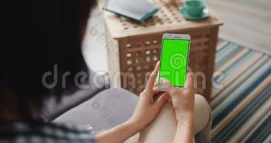 女孩触摸绿色模拟屏幕的现代智能手机使用设备在家里