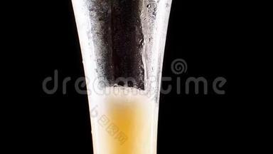 特写慢镜头：在黑色背景下，将冷啤酒倒入玻璃<strong>杯中</strong>，<strong>杯中</strong>有大量的水滴和气泡。