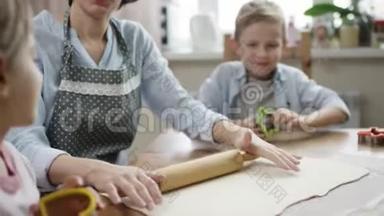 妈妈和孩子们一起在厨房的桌子上<strong>擀面皮</strong>做饼干，同时他们也在近距离讲述故事