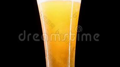 特写慢镜头：在黑色背景下，将冷啤酒倒入玻璃杯中，杯中有大量的水滴和气泡。