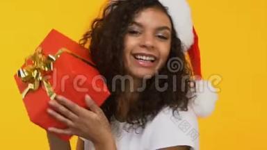 圣诞老人帽子里的棕色头发，带着礼物跳舞，圣诞节前大减价