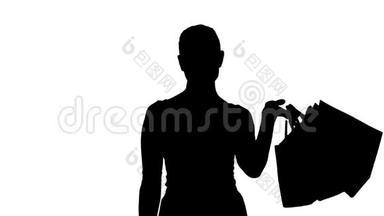 剪影让`去购物吧！ 带着购物袋走路的女人。