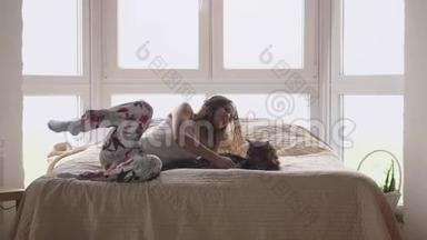 年轻漂亮的女人和她可爱的缅因州浣<strong>熊猫</strong>躺在床上放松，用手机听<strong>音乐</strong>。