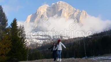 两个年轻的旅行妇女站在<strong>一座山</strong>的背景上，玩得很开心