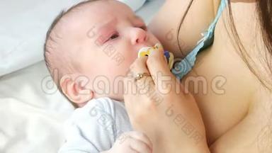 一个两个月的新生儿躺在母亲的手臂上，吮吸乳头。 妈妈试图让她的孩子睡觉