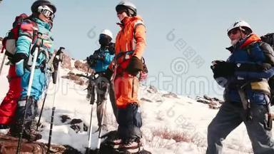 一群登山者站着用热水瓶喝茶。他们聊天，放松，准备爬山。
