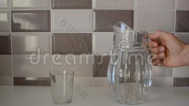 一个人把纯净水从玻璃瓶中倒入玻璃杯中