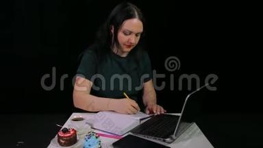 咖啡屋里的一个女人喝着黑背景的白色杯子里的咖啡，在看日记时写日记