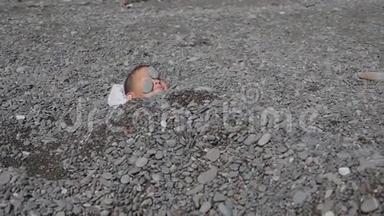 宝贝在海滩上。 男孩在海边装满了石头。 石头下面的孩子。 男孩胸前`海石
