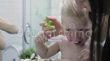 妈妈教孩子刷牙。 妈妈和孩子在刷牙时看镜子。 卫生概念。