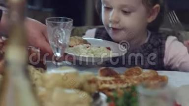 吃吧，我的小女孩。 一个女人给一个盘子的手，祝一个兴奋的小女孩吃肉、蔬菜和意大利面。 吃东西