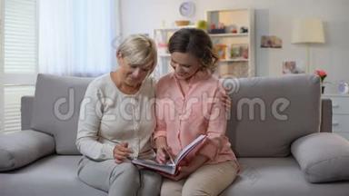 老太太和成年女儿一起看相册照片，家庭回忆