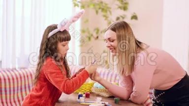 一个白人女孩手里拿着一个复活节彩蛋，但这次她的女儿手里拿着一把画笔