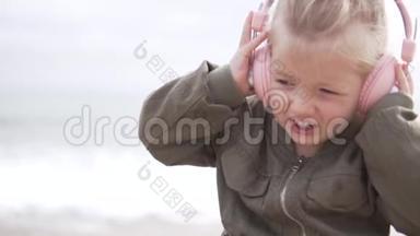 可爱的小女孩在海边用耳机听音乐