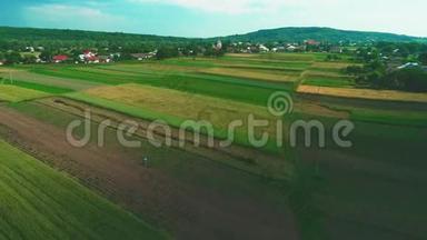 在阳光明媚的夏日，鸟瞰一个小村庄，农田，绿地和草地，在农村的农耕地。 4K.