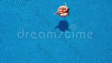 一位穿红色<strong>比基尼</strong>的<strong>女士</strong>躺在游泳池的甜甜圈上的空中景色