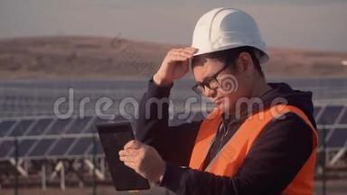亚洲外观工程师正在仔细研究平板电脑上的<strong>工作报告</strong>，并调整他头上的头盔