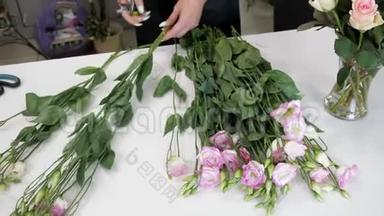 女花艺师工作时桌上放着白色和紫色的花，双手特写..