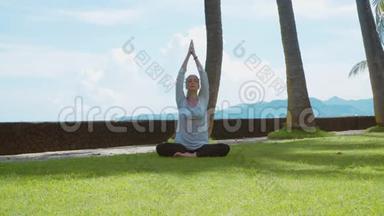 年轻女子做瑜伽练习，在巴厘岛的海洋海滩上放松莲花姿势，美丽的背景和自然的声音